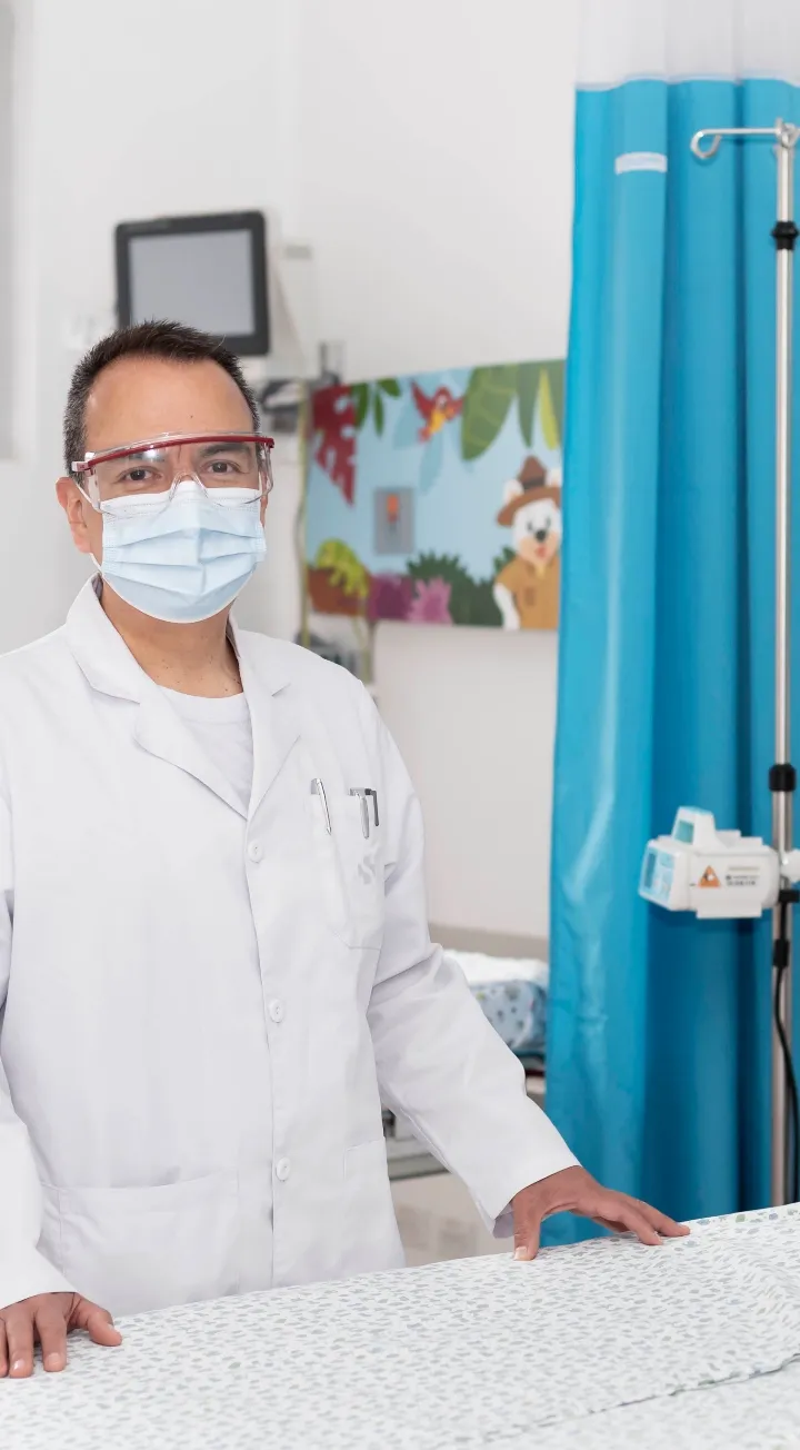 Médico en hospital pediátrico equipado con medidas de bioseguridad.