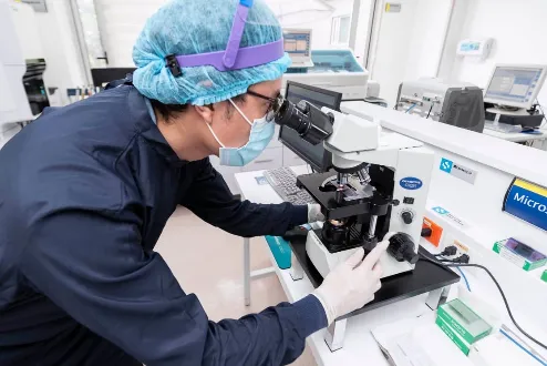 Laboratorio clínico con profesional de la salud usando microscopio para diagnóstico médico.