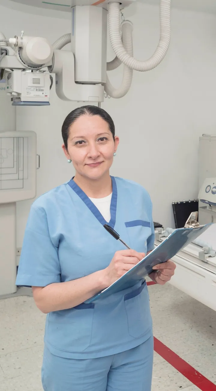 Profesional de la salud con uniforme azul registrando datos médicos de exámenes de laboratorio.